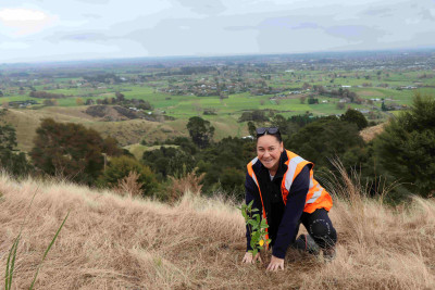 Image of Elly planting a plant on a hill