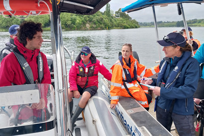 Staff wearing lifejackets on a vessel, deep in discussion on Lake Karapiro