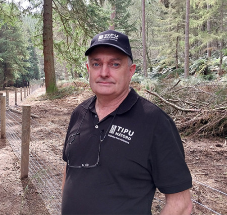 Image of a man wearing a cap and standing in a forest