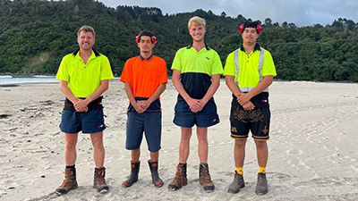 Image of the four younger men standing on sand